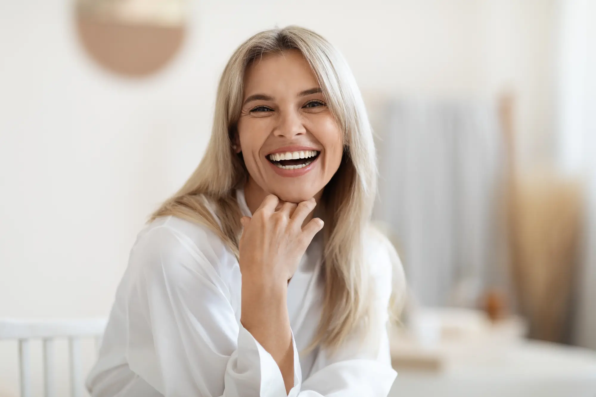 a woman smiling with her hand on her chin